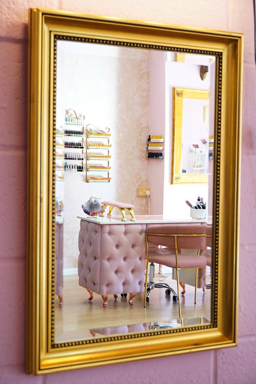 A rich gold mirror framing the salon’s blush beauty space
