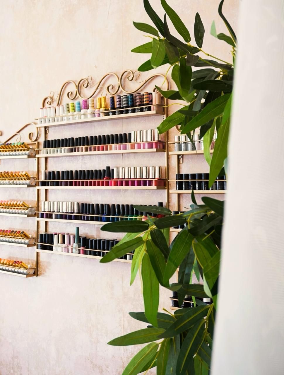 Nail colours on decorative gold shelves with green foliage